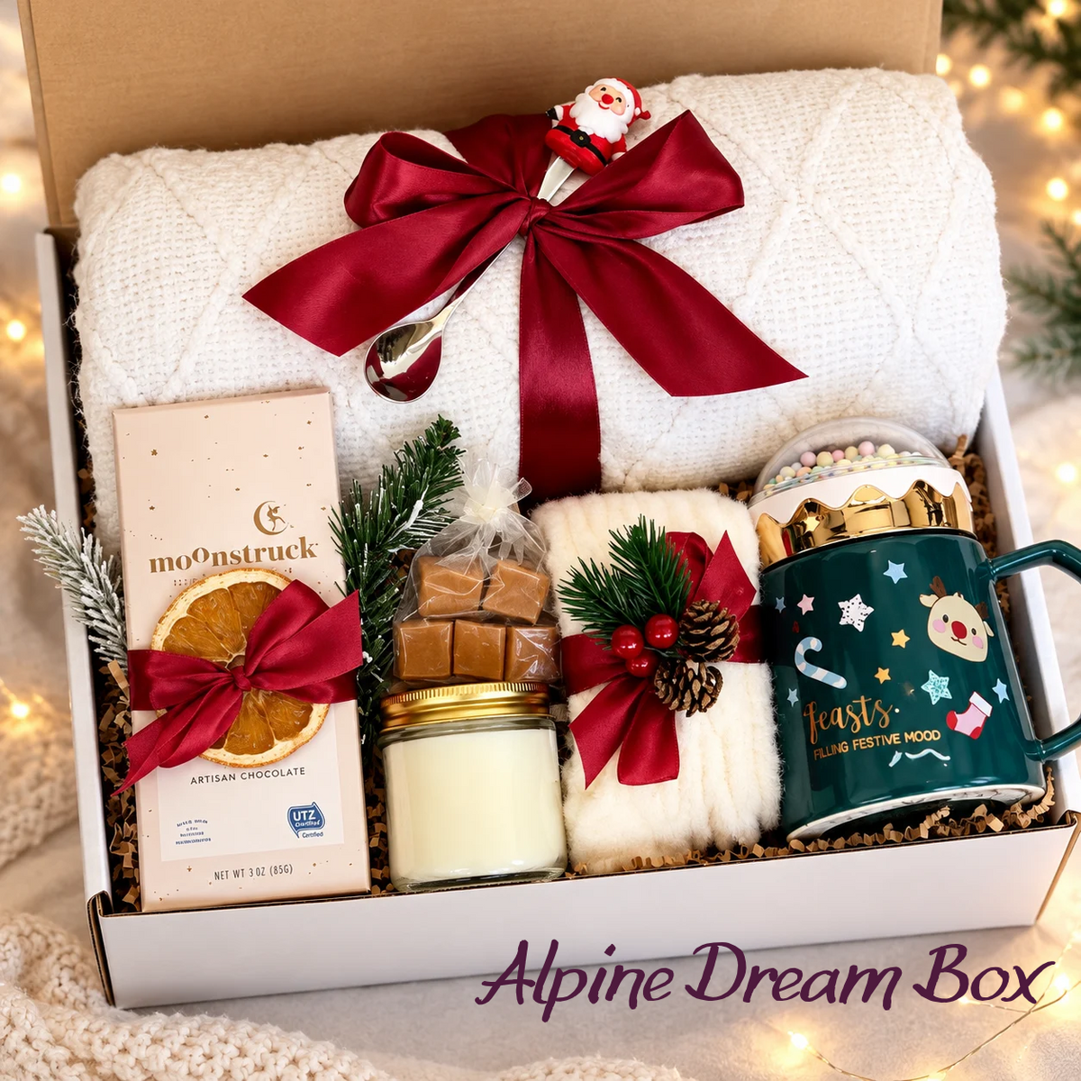 Alpine Dream Christmas gift box with a green festive mug, Moonstruck chocolate, white textured textiles and red ribbon bows.